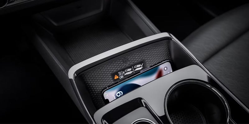 Close-up of the center console showing a wireless charging pad, phone, and cupholders
