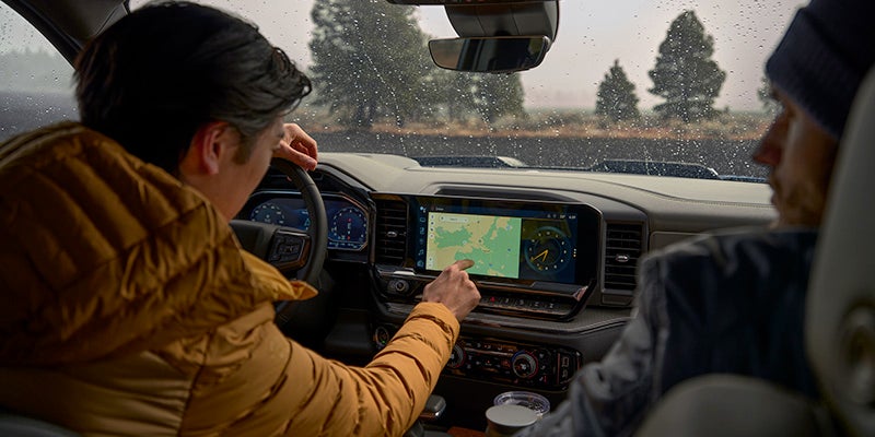 Driver interacts with the large infotainment screen inside a truck in the rain